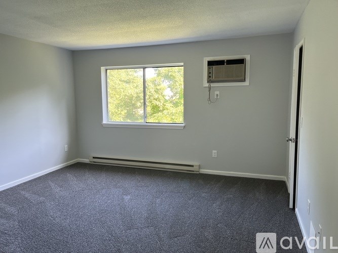 A room with a window and a wall-mounted air conditioning unit.