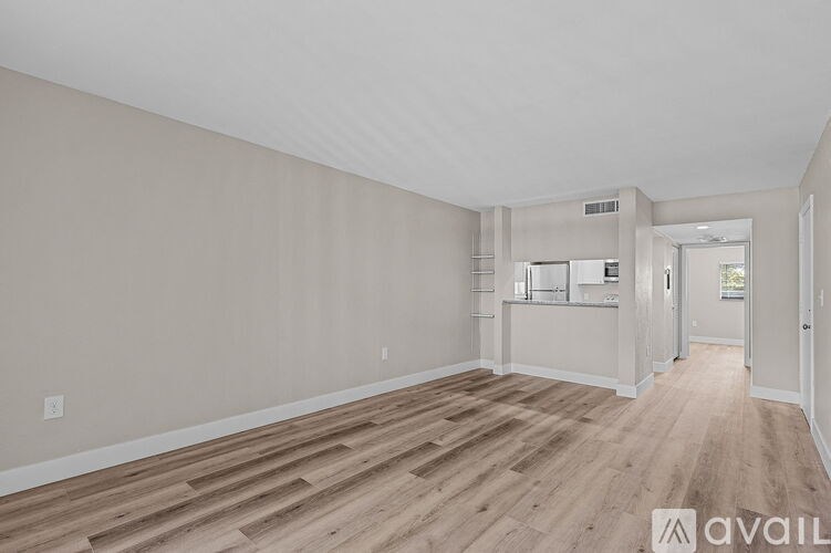 A spacious room with wooden flooring and white walls.