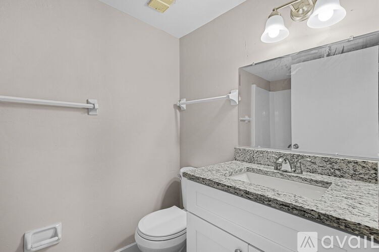 A bathroom with a toilet, sink, and mirror.