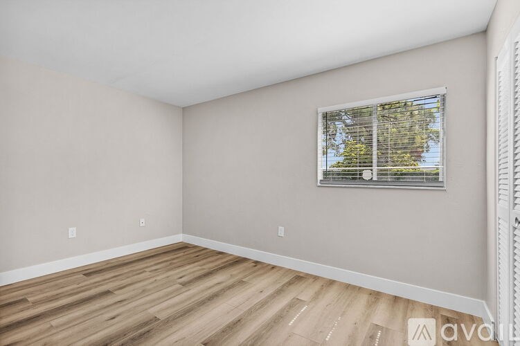 A room with wooden flooring and a window with blinds.