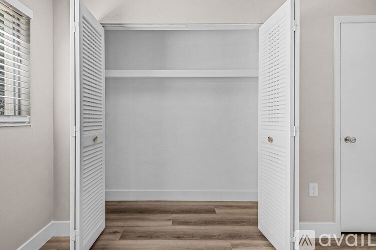 A white closet with a door and a shelf.