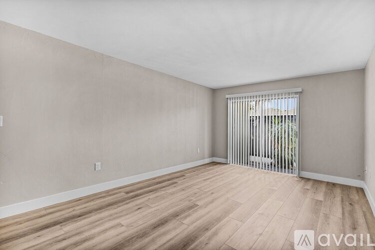 A room with wooden flooring and a window with blinds.