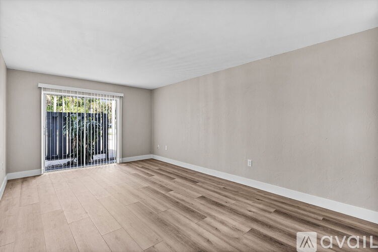 A room with wooden flooring and a sliding glass door.