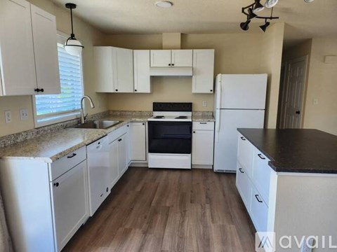 A kitchen with white cabinets and a black countertop.