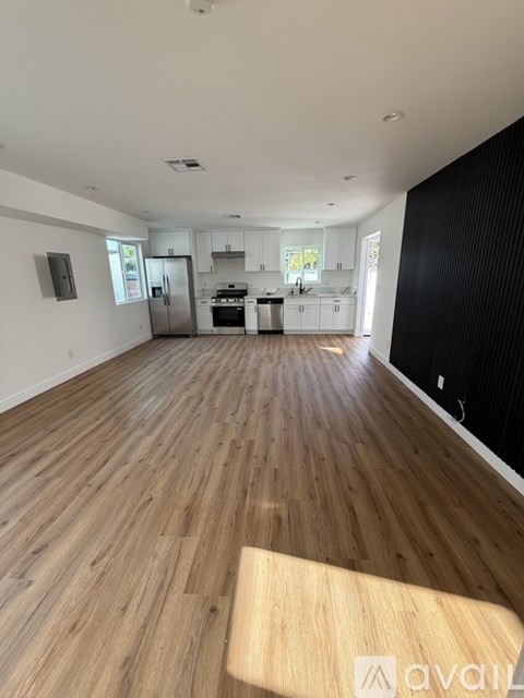 A spacious kitchen with wooden flooring and white walls.