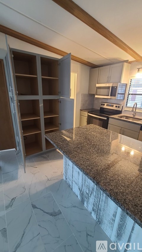 A kitchen with a marble countertop and a refrigerator with its door open.