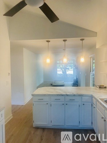 A kitchen with white cabinets and a ceiling fan.