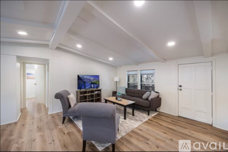 A living room with a grey sofa, a grey armchair, and a wooden floor.