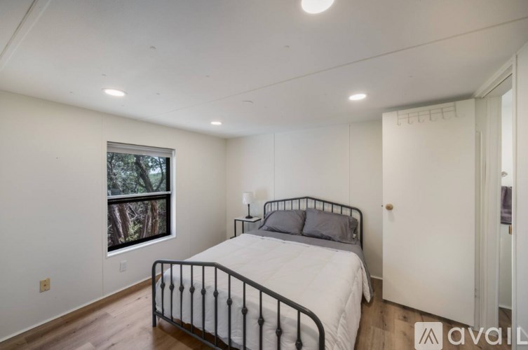 A bedroom with a large bed and a window overlooking trees.