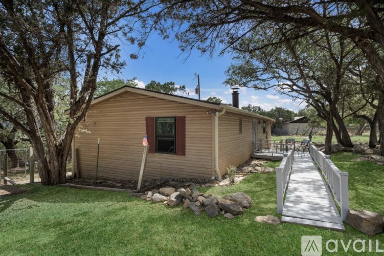 A house with a brown siding and a red window is surrounded by trees.