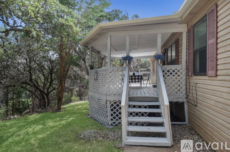 A wooden deck with a white railing and steps leading up to a house.