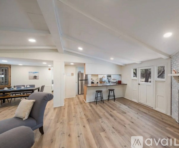 A living room with a grey sofa and a kitchen area in the background.