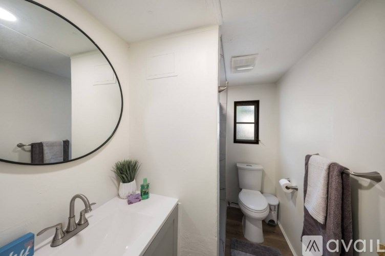 A bathroom with a toilet, sink, mirror, and towel.