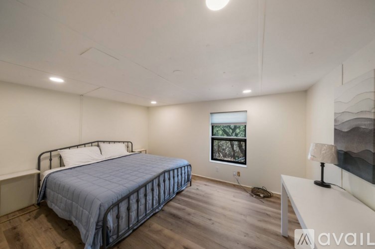 A bedroom with a bed, a nightstand, and a window.