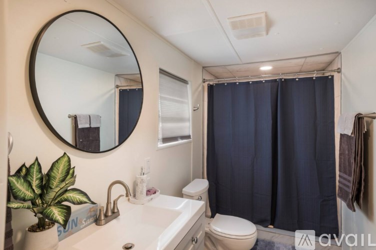 A bathroom with a white sink, toilet, and a round mirror.