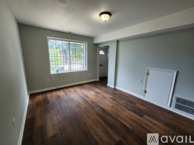 A room with wooden floors and a window overlooking a green area.
