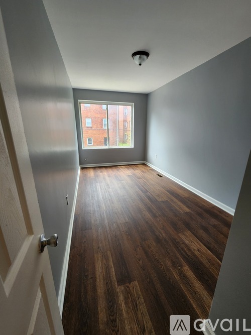 A room with wooden floors and a window showing a red brick building outside.