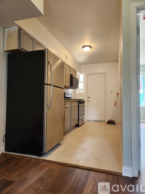 A kitchen with a black fridge and wooden floors.