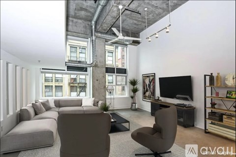 A modern living room with a grey sofa set, a television, and a large window.