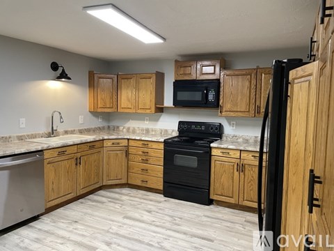 A kitchen with wooden cabinets and black appliances.