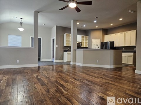 A spacious kitchen and living room with wood flooring and a ceiling fan.