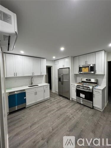 A kitchen with white cabinets and a wooden floor.
