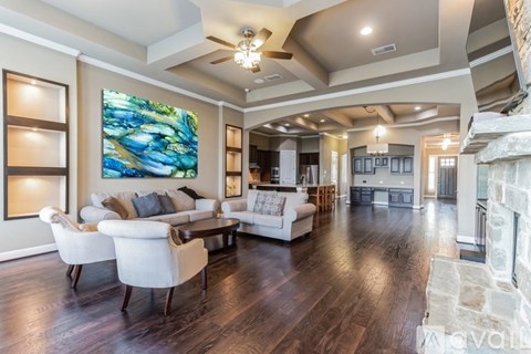 A living room with a large painting on the wall and a fireplace on the right side.
