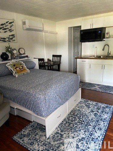 A bedroom with a bed, chair, and a television.