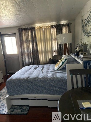 A bedroom with a bed, a chair, and a lamp.