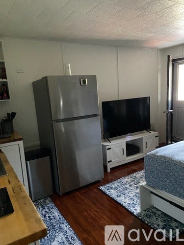 A kitchen with a refrigerator, a television, and a bed.