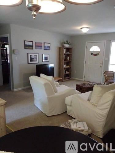A living room with a black table and two white chairs.