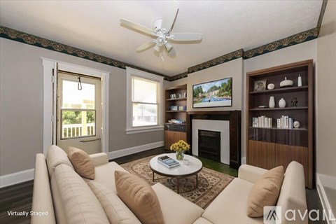 A living room with a white couch, a coffee table, a fireplace, and a painting on the wall.