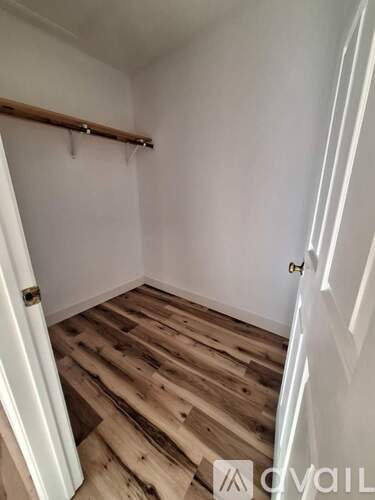 A room with wooden floors and a window letting in sunlight.