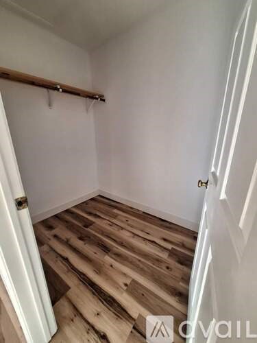 A room with wooden floors and a window letting in sunlight.