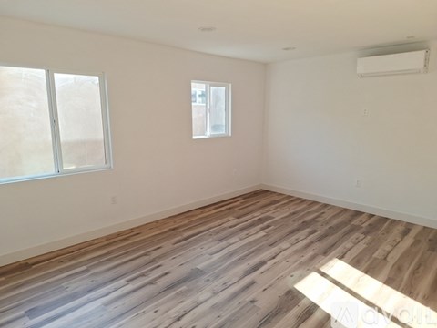 A room with a door, window, and a wall-mounted air conditioner.