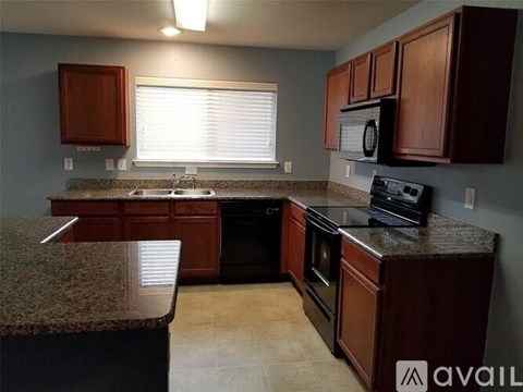 A kitchen with brown cabinets and granite countertops.