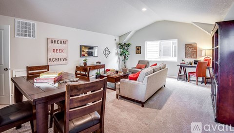 A living room with a couch, chairs, and a table with a sign that says "Dream Seek Achieve".