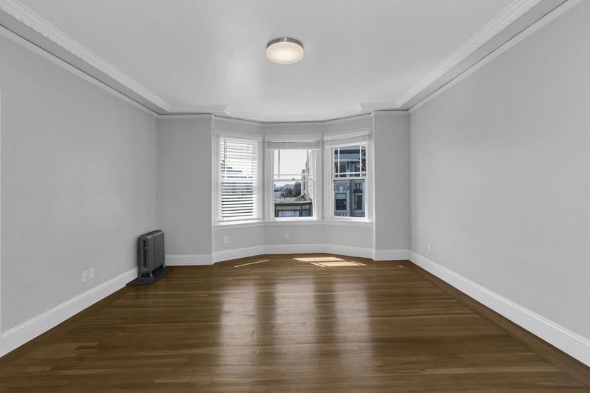 an empty living room with hardwood floors and a bay window