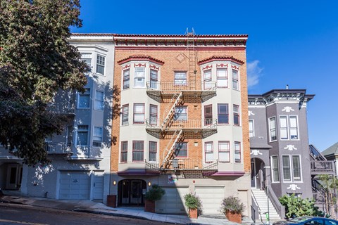A row of houses with a blue car parked in front of the first one.