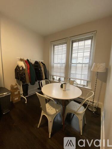 A room with a table, chairs and clothes hanging up.