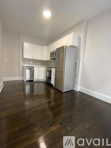 A kitchen with white cabinets and a refrigerator.