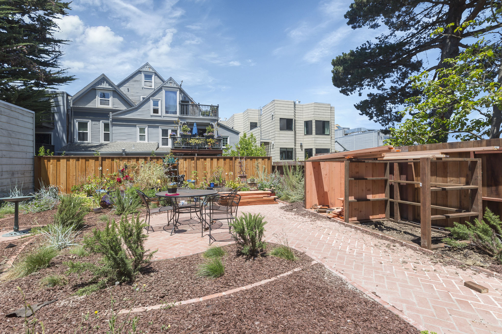 A backyard with a table and chairs surrounded by a wooden fence.