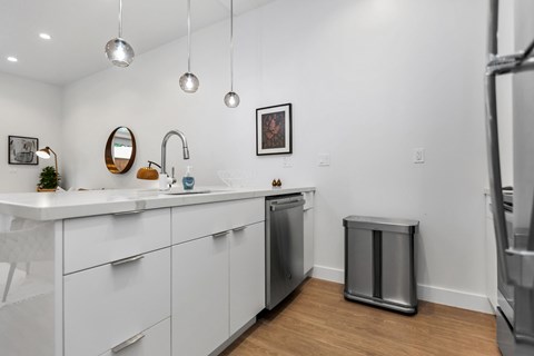 A modern kitchen with white cabinets and a stainless steel dishwasher.
