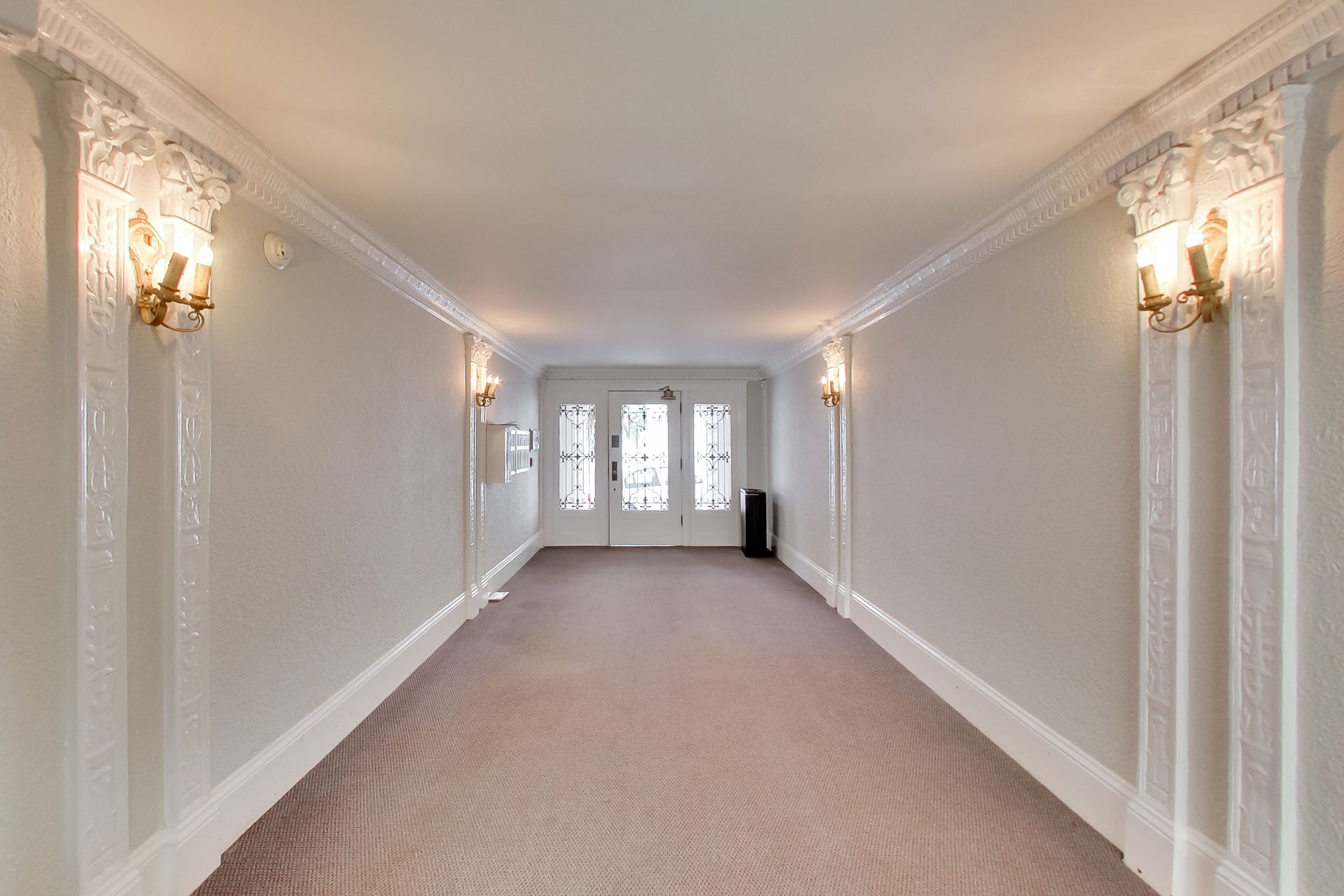 A long hallway with white walls and a carpeted floor.