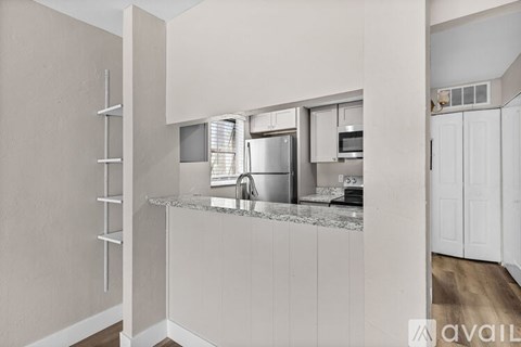 A kitchen with white cabinets and a marble countertop.