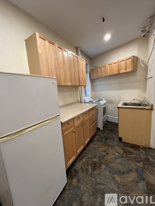 A kitchen with a white refrigerator and wooden cabinets.