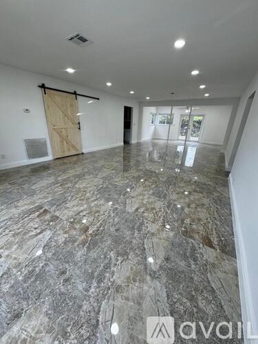 A spacious room with marble flooring and a wooden door.