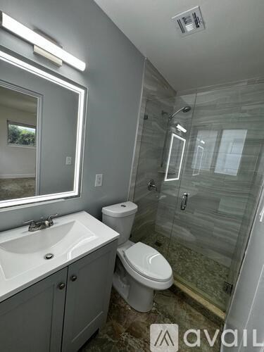 A bathroom with a toilet, sink, and glass shower stall.