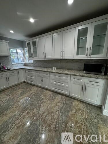 A kitchen with granite countertops and white cabinets.