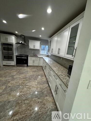 A kitchen with granite countertops and white cabinets.
